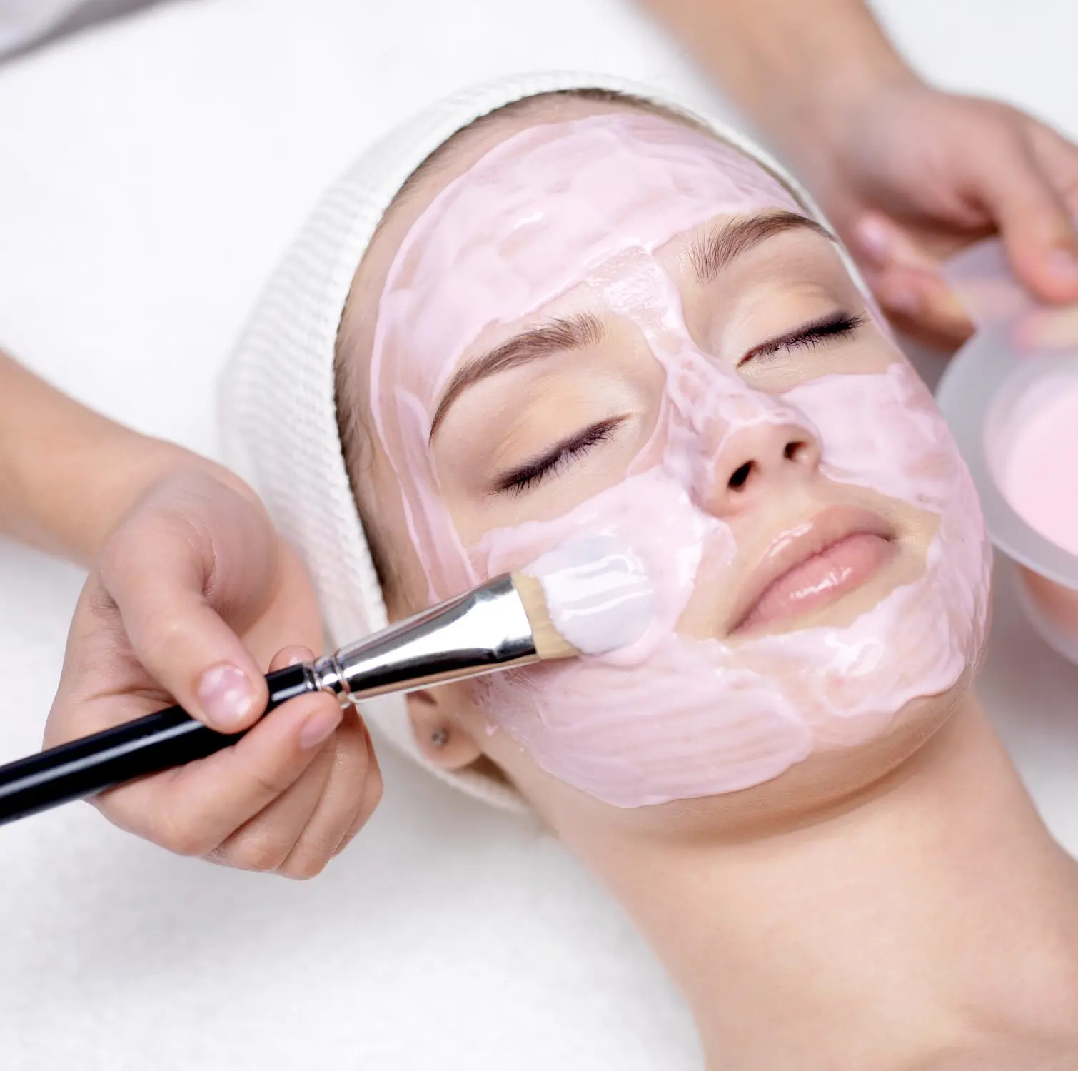 Girl receiving cosmetic pink facial mask