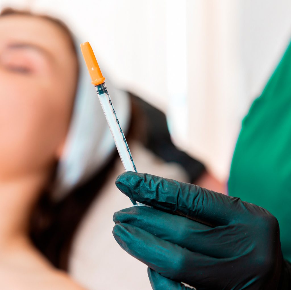Beaitician holds a syringe with an injection Mesotherapy
