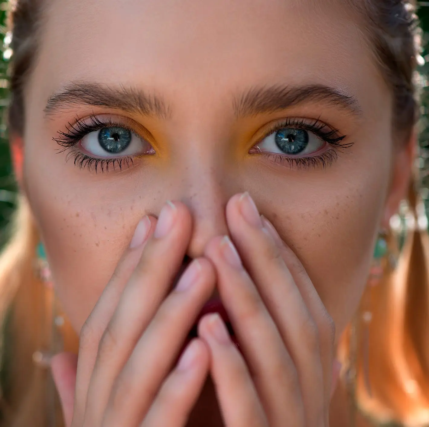 Beautiful young woman covered part of her face by the hands