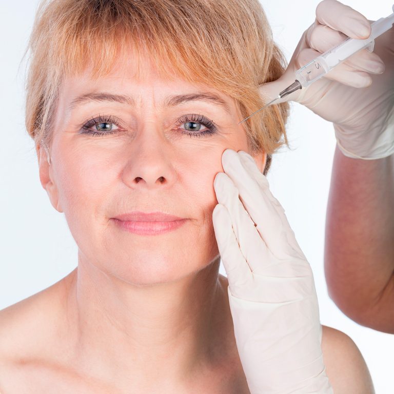 Doctor does injection to elderly woman s face