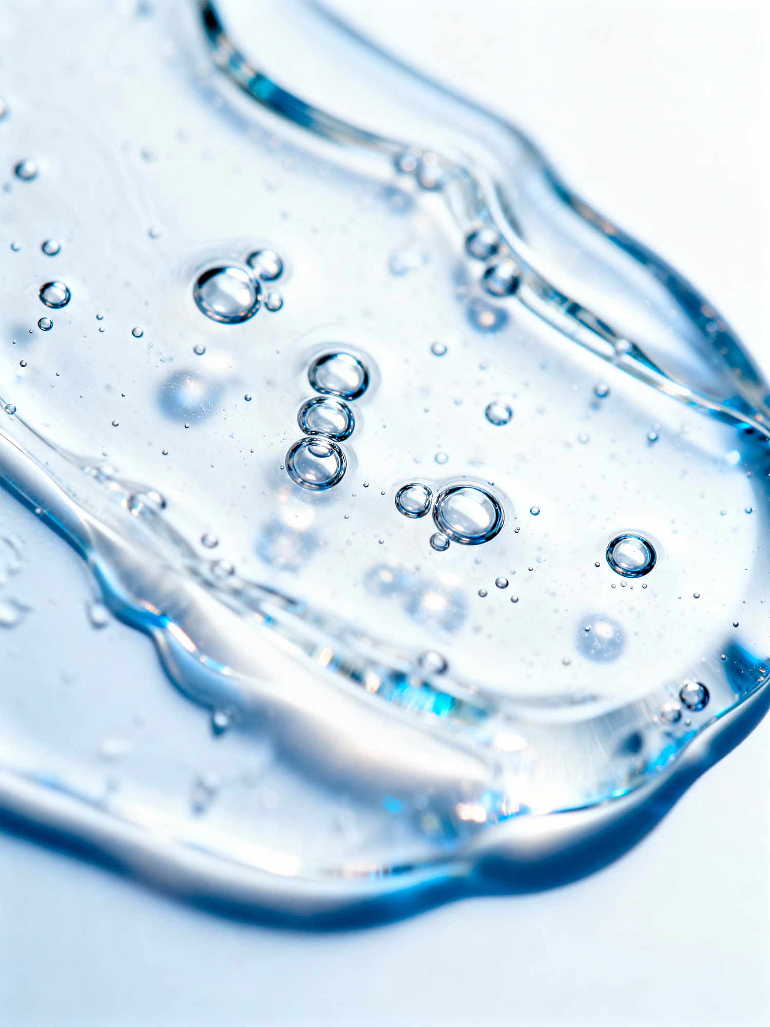 An extreme macro shot of a clear, viscous hyaluronic acid serum gel, showing its pure and hydrating texture with small bubbles.